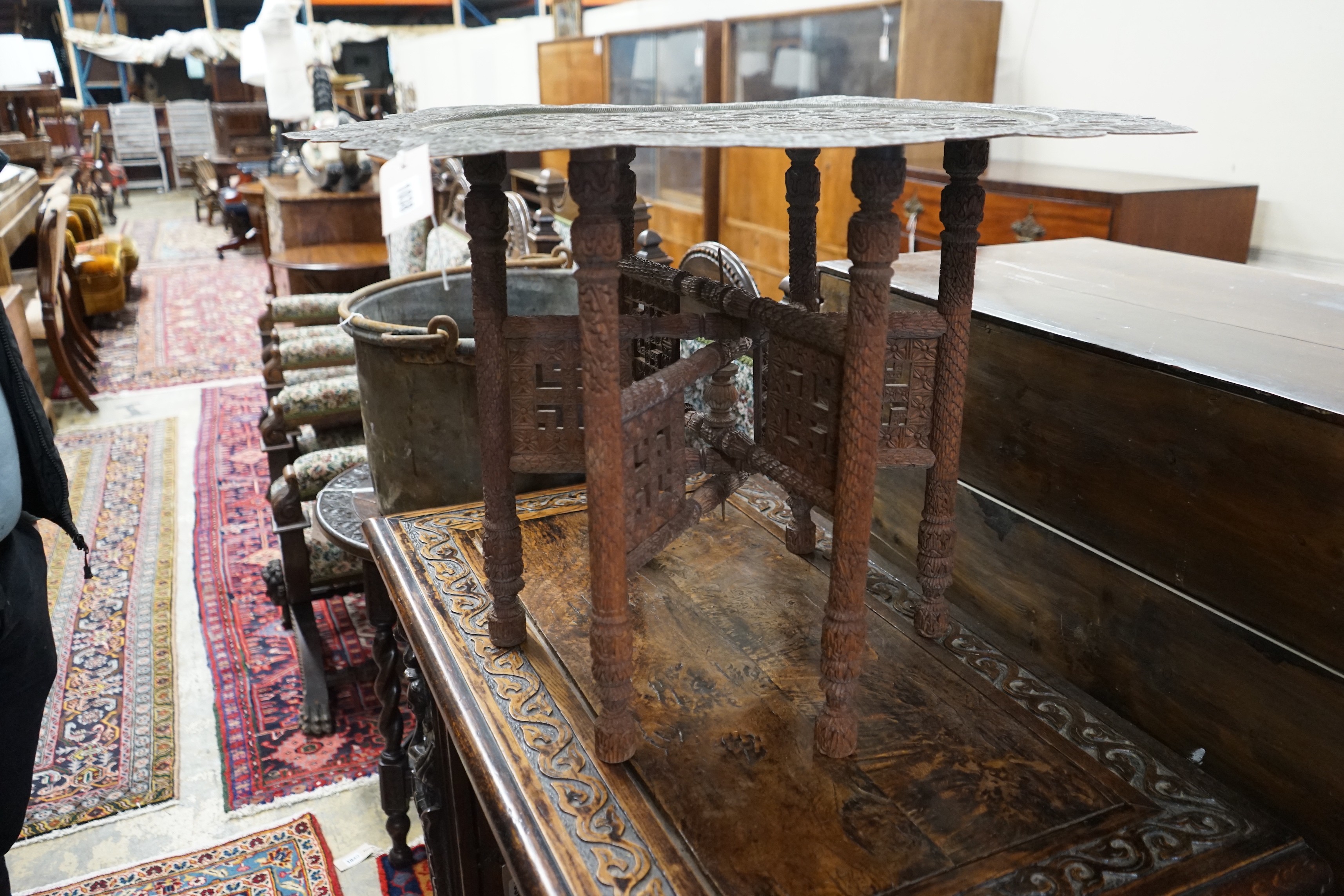 An Indian circular pierced brass tray top table, on carved folding stand, diameter 83cm, height 55cm